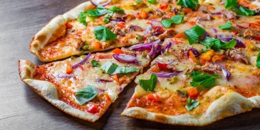 Mozzarella peyniri, soğan, ton balığı, domates sosu, biber, fesleğen ile pizza. Ahşap masada İtalyan Pizza