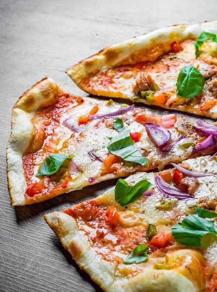 Pizza with Mozzarella cheese, onion, tuna fish, tomato sauce, pepper, basil. Italian pizza on wooden table