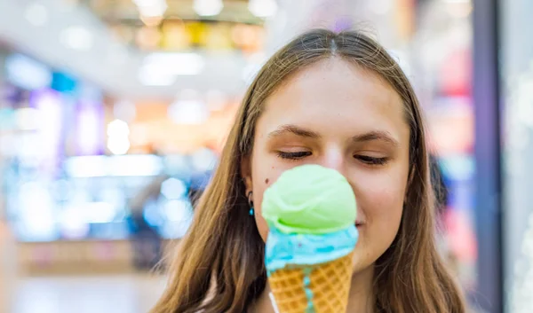 ショッピングモールでおいしいコーンアイスクリームを食べる長い髪を持つ若いティーンエイジャーブルネットの女の子 — ストック写真