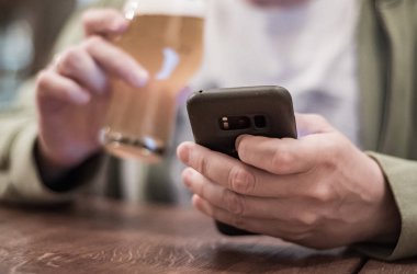 Erkek eli kamerayı kapat, akıllı telefonu tut, bira iç ve barda veya barda mesaj oku.