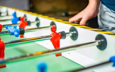 Bir adam masa futbolu oynar. Kicker oynayan adamın ellerinin detayı