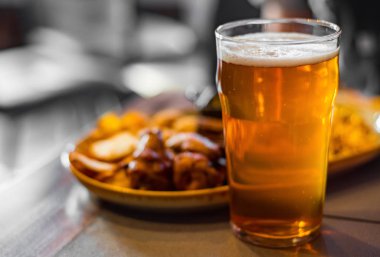 bar veya pub ahşap masa arka plan üzerinde aperatifler ile soğuk bira ve tabak cam