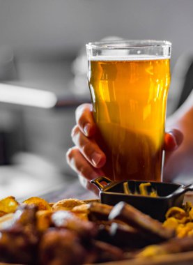 bar veya pub ahşap masa arka plan üzerinde aperatifler ile soğuk bira ve tabak cam ile adam el