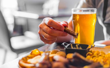 bar veya pub ahşap masa arka plan üzerinde aperatifler ile soğuk bira ve tabak cam ile adam el