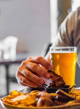 bar veya pub ahşap masa arka plan üzerinde aperatifler ile soğuk bira ve tabak cam ile adam el