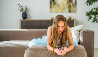 evde kanepede yatan uzun saçlı genç genç esmer kız portresi akıllı telefon kullanarak eğlenin