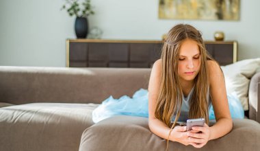 evde kanepede yatan uzun saçlı genç genç esmer kız portresi akıllı telefon kullanarak eğlenin