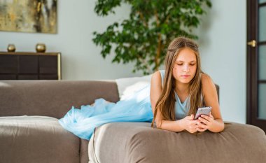 evde kanepede yatan uzun saçlı genç genç esmer kız portresi akıllı telefon kullanarak eğlenin