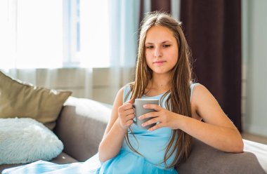 evde fincan ile kanepede oturan uzun saçlı genç genç esmer kız portresi