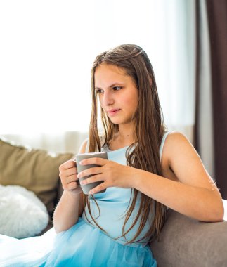 evde fincan ile kanepede oturan uzun saçlı genç genç esmer kız portresi