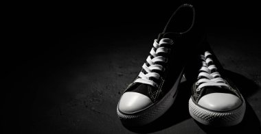 Kopyalama alanı ile koyu siyah arka plan üzerinde yeni siyah spor ayakkabı çifti.