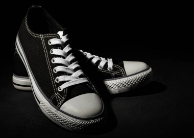 Kopyalama alanı ile koyu siyah arka plan üzerinde yeni siyah spor ayakkabı çifti.