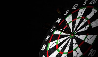 Dart ok ile Dart tahtası kopya alanı ile koyu siyah bir arka plan üzerinde merkezi isabet.