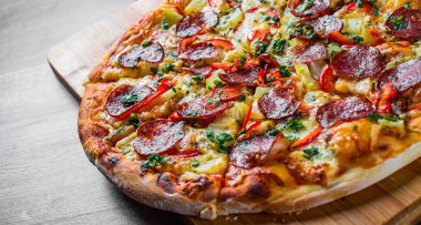 Mozzarella peynirli Pepperoni Pizza, salam, biber. Baharatlar ve taze fesleğen. Ahşap masa arka planda İtalyan pizza