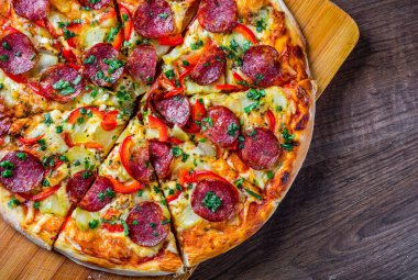 Mozzarella peynirli Pepperoni Pizza, salam, biber. Baharatlar ve taze fesleğen. Ahşap masa arka planda İtalyan pizza