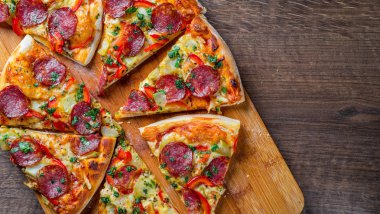 Mozzarella peynirli Pepperoni Pizza, salam, biber. Baharatlar ve taze fesleğen. Ahşap masa arka planda İtalyan pizza