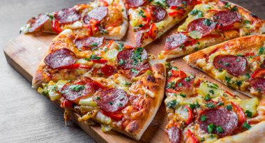 Mozzarella peynirli Pepperoni Pizza, salam, biber. Baharatlar ve taze fesleğen. Ahşap masa arka planda İtalyan pizza