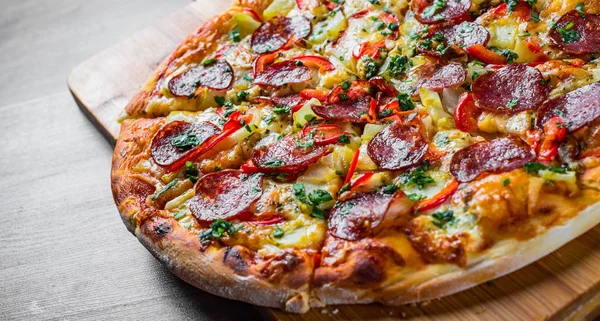 Mozzarella peynirli Pepperoni Pizza, salam, biber. Baharatlar ve taze fesleğen. Ahşap masa arka planda İtalyan pizza