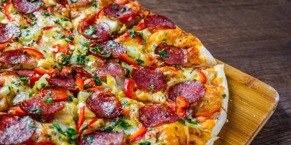 Mozzarella peynirli Pepperoni Pizza, salam, biber. Baharatlar ve taze fesleğen. Ahşap masa arka planda İtalyan pizza