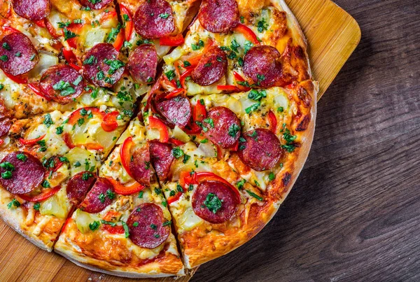 Mozzarella peynirli Pepperoni Pizza, salam, biber. Baharatlar ve taze fesleğen. Ahşap masa arka planda İtalyan pizza