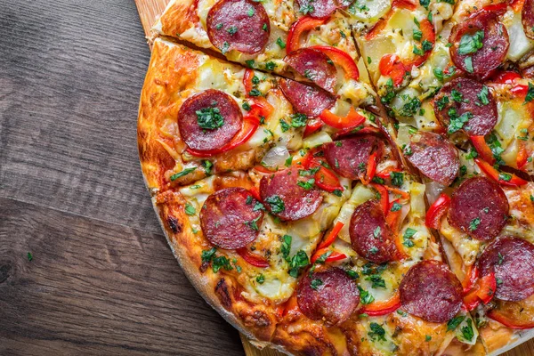 Mozzarella peynirli Pepperoni Pizza, salam, biber. Baharatlar ve taze fesleğen. Ahşap masa arka planda İtalyan pizza