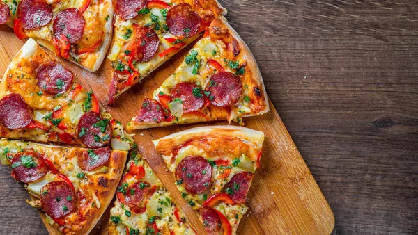 Mozzarella peynirli Pepperoni Pizza, salam, biber. Baharatlar ve taze fesleğen. Ahşap masa arka planda İtalyan pizza