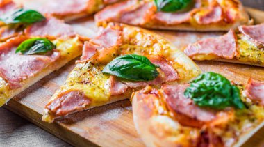 Pizza Mozzarella peynir, jambon, domates sosu, biber, Baharat ve Taze fesleğen ile. Ahşap masa arka planda İtalyan pizza