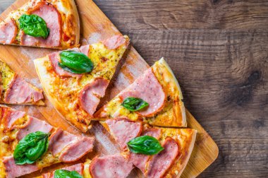 Pizza Mozzarella peynir, jambon, domates sosu, biber, Baharat ve Taze fesleğen ile. Ahşap masa arka planda İtalyan pizza