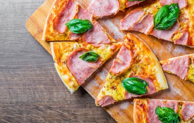 Pizza Mozzarella peynir, jambon, domates sosu, biber, Baharat ve Taze fesleğen ile. Ahşap masa arka planda İtalyan pizza