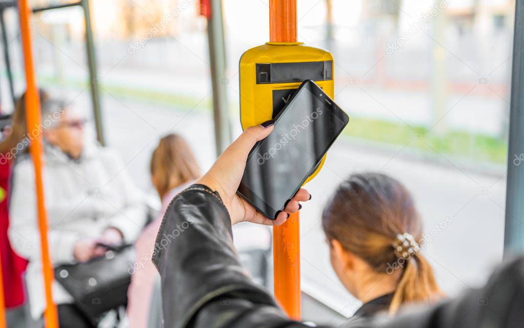 woman hand Paying conctactless with smartphone in public transport