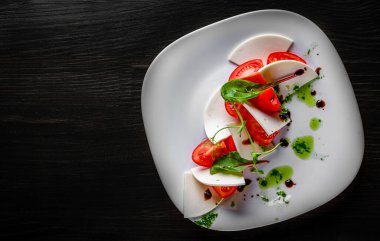 Beyaz tabakta domates ve peynirli İtalyan Caprese salatası.