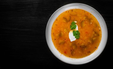 Salatalık turşulu çorba ve beyaz tabakta inci arpa siyah ahşap masa zemininde