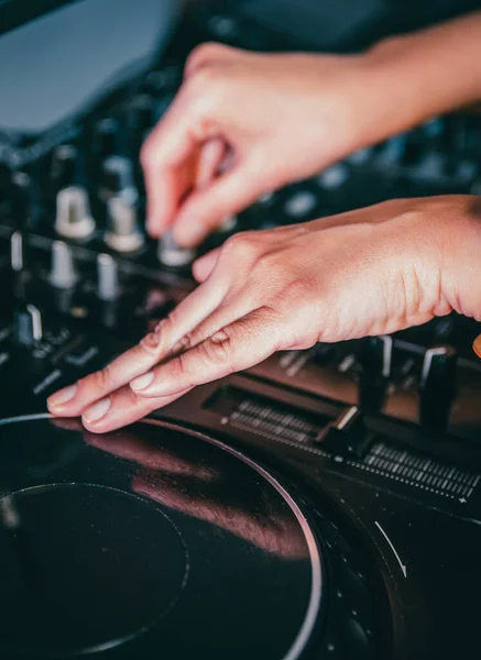 DJ Hands creating and regulating music on dj console mixer in concert nightclub stage.