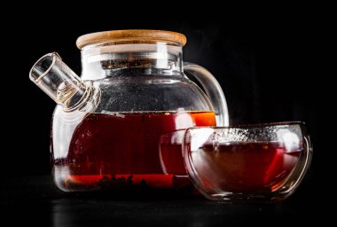 Çay demliği ve siyah arka planda bir fincan puer çayı.