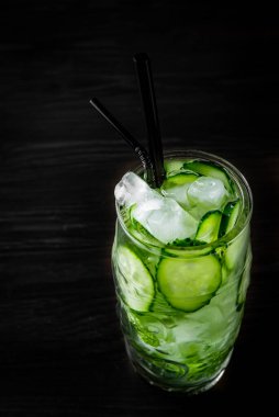 Salatalık ve naneli limonata siyah ahşap masa arkasında bir bardakta.