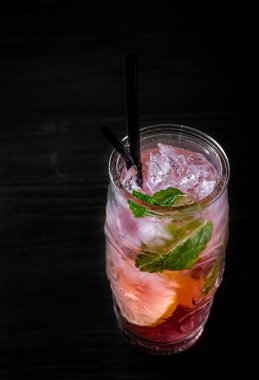 Bir bardak ferahlatıcı karpuz limonatası. Siyah ahşap masa arkasında buzlu.