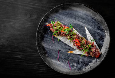 Siyah ahşap masa arkasında çiğ et tartartarı.