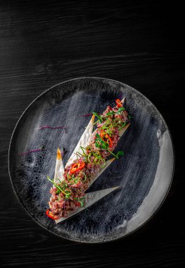 Siyah ahşap masa arkasında çiğ et tartartarı.