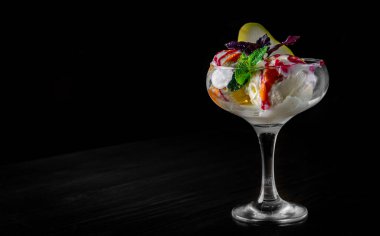 Lezzetli dondurma. Siyah arka plandaki meyvelerle süslenmiş.