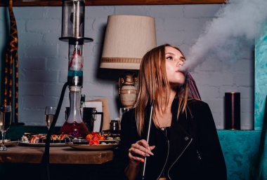 Genç bir kadın restoranda nargile içiyor..