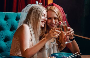 Kafede oturup suşi yiyen ve şarap içen iki genç kadın.