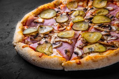  Mozzarella peynirli, jambonlu, domates soslu, biberli, salatalıklı ve mantarlı pizza. Koyu gri arka planda İtalyan pizzası