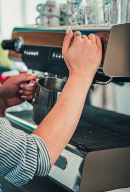 Barmen kahve makinesinde sıcak süt hazırlıyor.