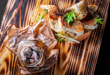 Ahşap masada cam kavanozda marine edilmiş mantarlar.