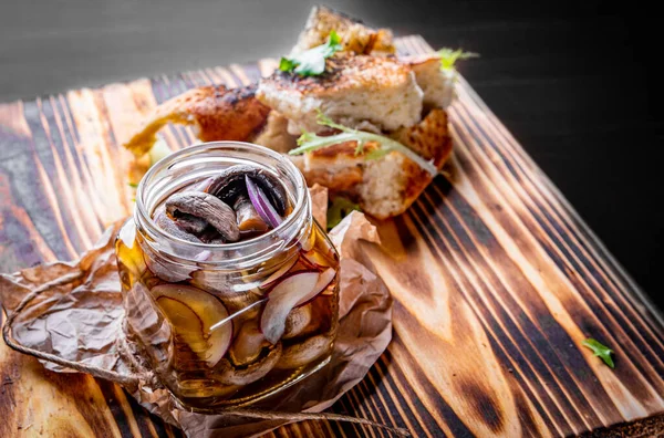 Ahşap masada cam kavanozda marine edilmiş mantarlar.