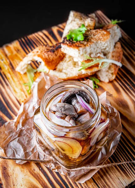 Ahşap masada cam kavanozda marine edilmiş mantarlar.