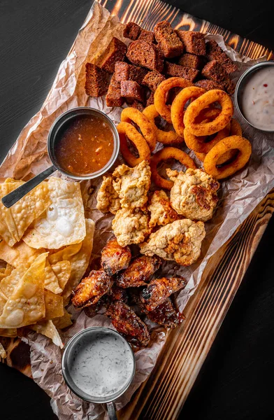 Sörtányér Fűszeres Csirkeszárnyakkal Chipsszel Sült Hagymakarikákkal Sajtgolyókkal Kenyérrel Tartármártással Asztalon Stock Kép