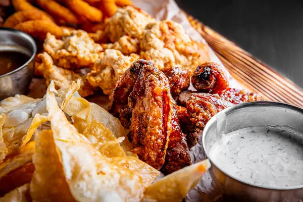 닭고기 날개가 감자칩 감자튀김 치즈볼 타타르 소스를 테이블에 스톡 사진