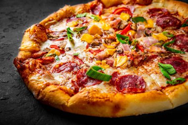 Mozzarella peynirli pizza, salam, tavuk eti, sığır eti, jambon, domates sosu, biber, baharat. Koyu gri arka planda İtalyan pizzası