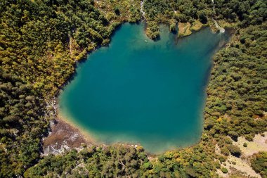 Mavi bir göl ve yeşil ormanlar üzerindeki dağların havadan görünüşü